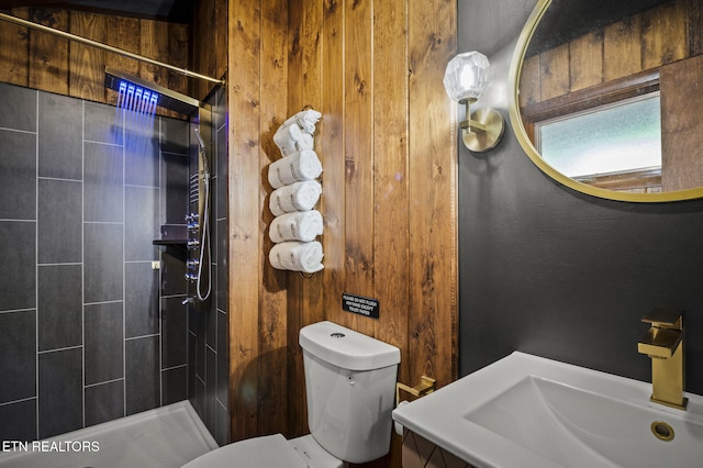 bathroom featuring a tile shower, toilet, and sink