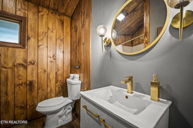 bathroom featuring toilet, wooden walls, and sink