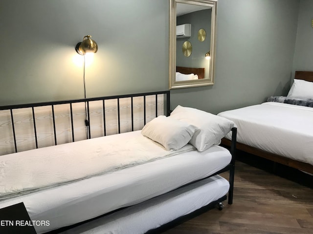 bedroom featuring dark hardwood / wood-style flooring and a wall mounted air conditioner