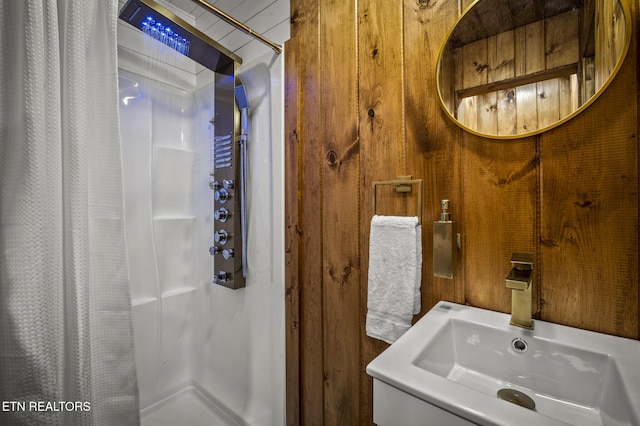 bathroom with curtained shower, wood walls, and sink