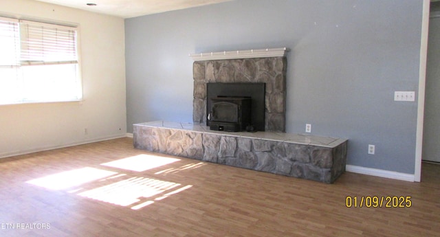 unfurnished living room with wood-type flooring and a wood stove