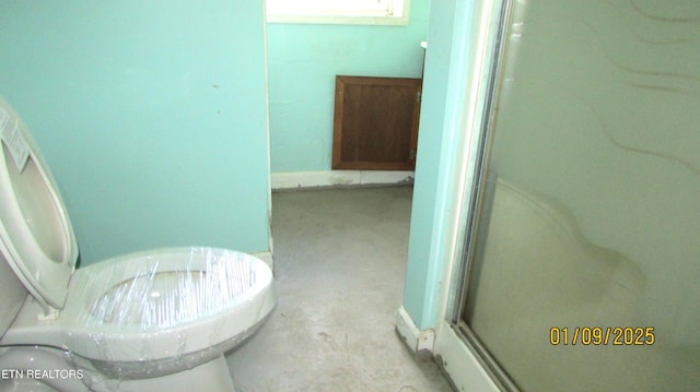 bathroom with walk in shower, toilet, and concrete floors