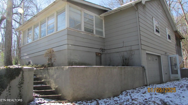 view of snow covered exterior with a garage