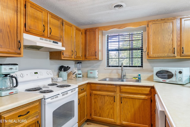 kitchen with a textured ceiling, white appliances, and sink