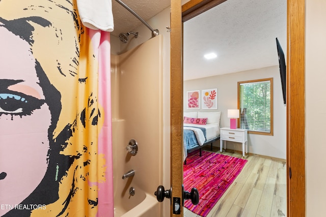 bathroom with hardwood / wood-style floors, shower / bath combination with curtain, and a textured ceiling