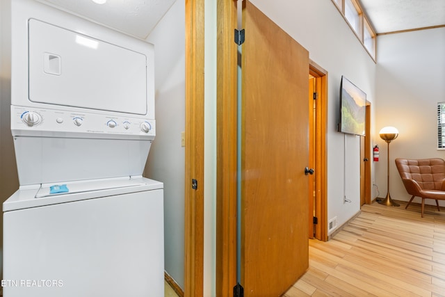 laundry area with light hardwood / wood-style flooring and stacked washer and clothes dryer