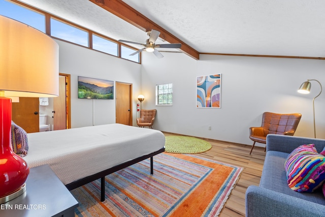 bedroom with connected bathroom, ceiling fan, vaulted ceiling with beams, wood-type flooring, and a textured ceiling