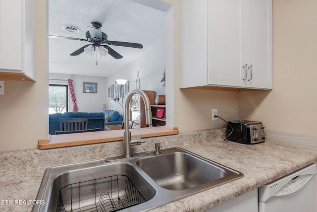 kitchen featuring ceiling fan, sink, white dishwasher, a textured ceiling, and white cabinets