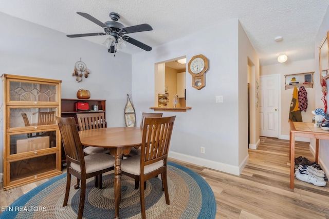 dining room with ceiling fan, sink, a textured ceiling, and light hardwood / wood-style flooring