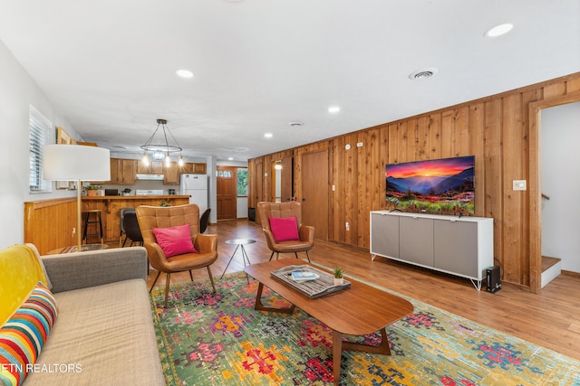 living room featuring wood walls, light hardwood / wood-style flooring, and a healthy amount of sunlight