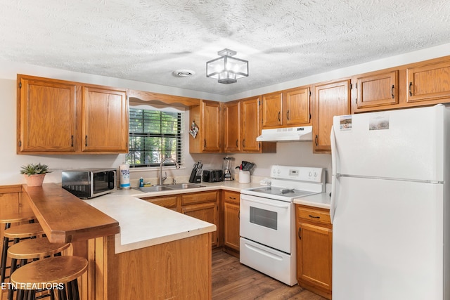 kitchen featuring dark hardwood / wood-style flooring, kitchen peninsula, sink, and white appliances