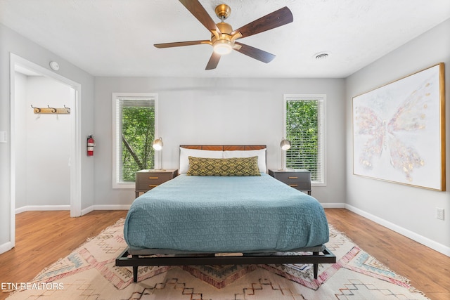 bedroom with ceiling fan, light hardwood / wood-style floors, and multiple windows