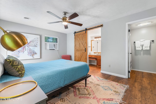 bedroom featuring a barn door, ceiling fan, ensuite bathroom, and a textured ceiling