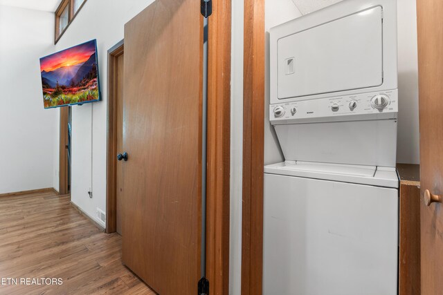 laundry room with light hardwood / wood-style floors and stacked washer / dryer