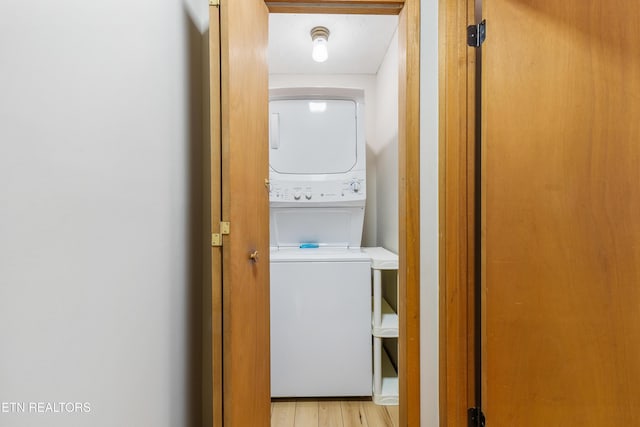 clothes washing area featuring a textured ceiling, light wood-type flooring, and stacked washer and dryer