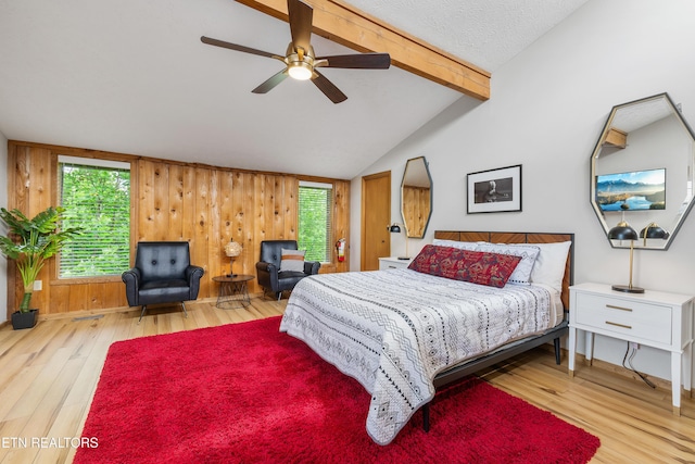 bedroom featuring hardwood / wood-style floors, vaulted ceiling with beams, multiple windows, and ceiling fan