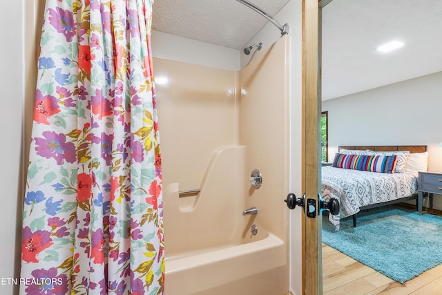 bathroom with hardwood / wood-style floors, shower / bath combination with curtain, and a textured ceiling