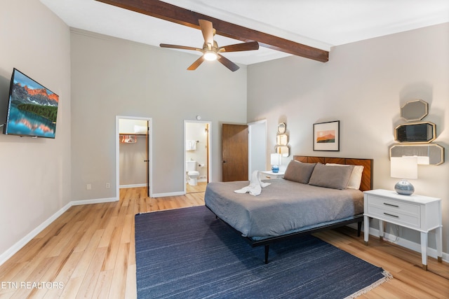 bedroom with ceiling fan, beam ceiling, connected bathroom, and light hardwood / wood-style flooring