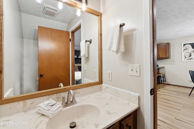 bathroom featuring hardwood / wood-style floors, vanity, and a textured ceiling