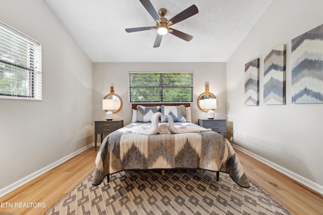 bedroom featuring multiple windows, hardwood / wood-style floors, vaulted ceiling, and ceiling fan