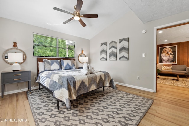 bedroom with a textured ceiling, ceiling fan, light hardwood / wood-style flooring, and vaulted ceiling