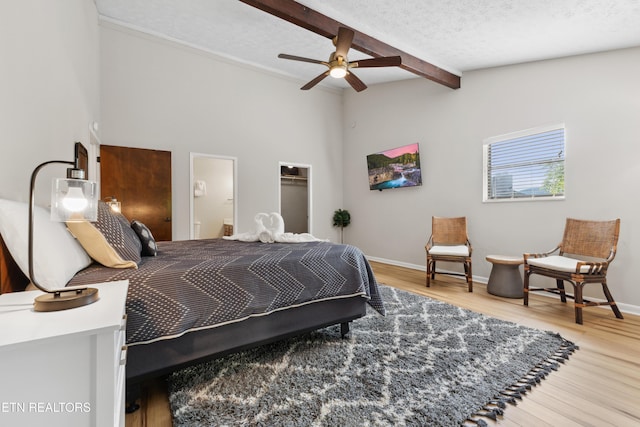 bedroom featuring a walk in closet, a textured ceiling, ceiling fan, wood-type flooring, and a closet