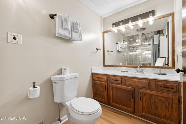 bathroom featuring walk in shower, hardwood / wood-style floors, a textured ceiling, toilet, and vanity