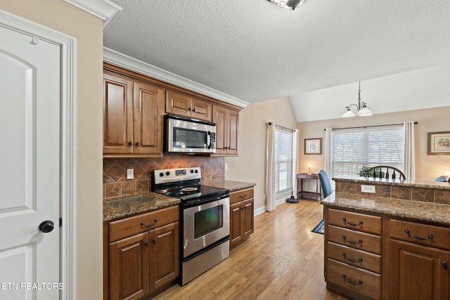 kitchen with a chandelier, appliances with stainless steel finishes, decorative light fixtures, lofted ceiling, and tasteful backsplash