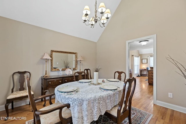 dining space with high vaulted ceiling, an inviting chandelier, and light wood-type flooring