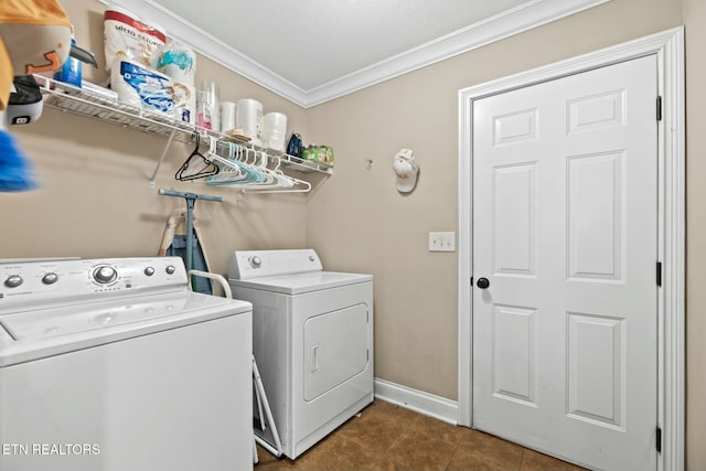 clothes washing area with dark tile patterned flooring, washing machine and dryer, and crown molding