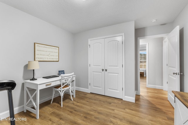 office space featuring light wood-type flooring and a textured ceiling