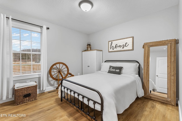 bedroom with a textured ceiling and light wood-type flooring