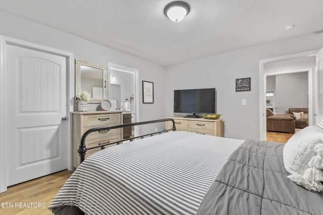 bedroom with a textured ceiling and light hardwood / wood-style flooring