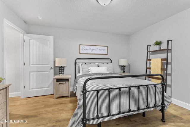 bedroom with a textured ceiling and light hardwood / wood-style flooring