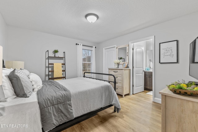 bedroom featuring ensuite bathroom, light hardwood / wood-style floors, and a textured ceiling