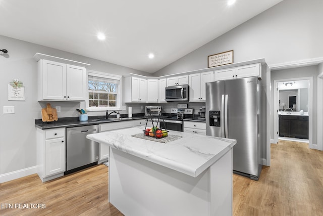 kitchen with white cabinetry, lofted ceiling, sink, a center island, and stainless steel appliances