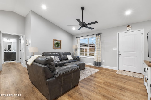 living room with vaulted ceiling, ceiling fan, and light wood-type flooring