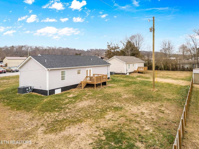 rear view of house featuring a wooden deck, central AC, and a lawn