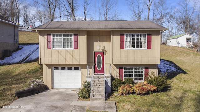 raised ranch featuring a front lawn, central air condition unit, and a garage