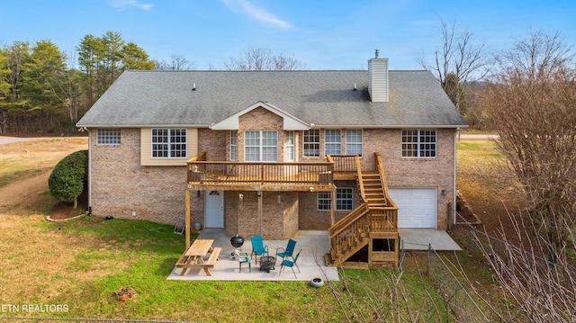 rear view of house with a lawn, a fire pit, a garage, a deck, and a patio