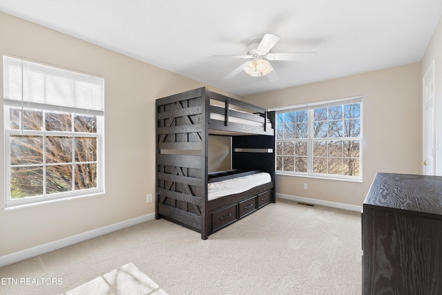 carpeted bedroom featuring multiple windows and ceiling fan