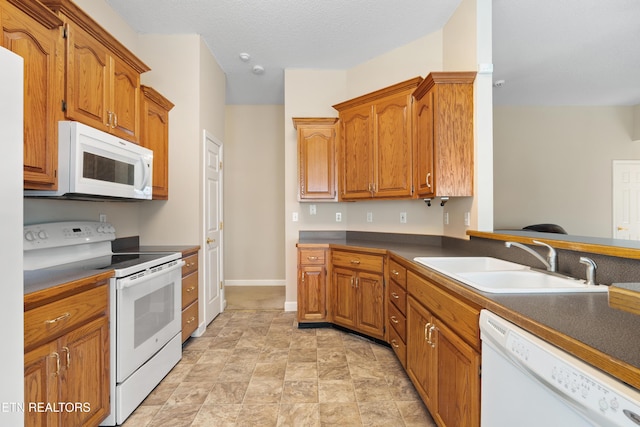 kitchen with a textured ceiling, white appliances, and sink