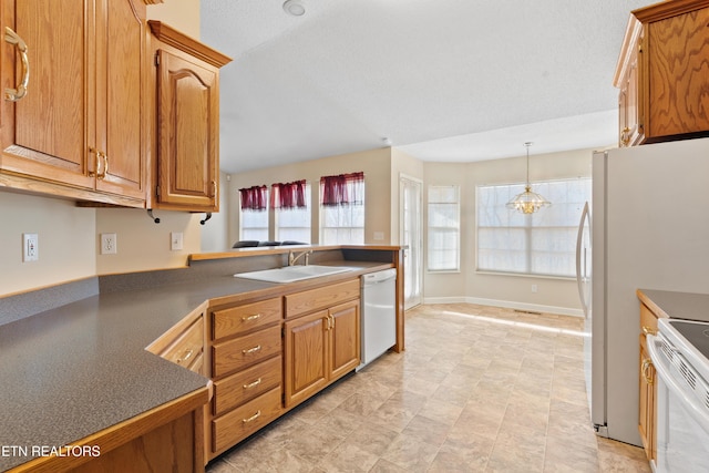 kitchen featuring a textured ceiling, white appliances, sink, a notable chandelier, and hanging light fixtures