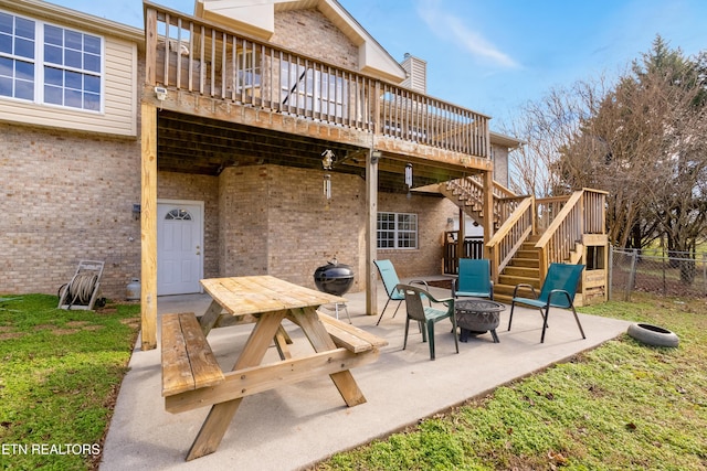 back of house with a lawn, a wooden deck, a patio area, and a fire pit