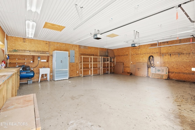 garage with electric panel, sink, a garage door opener, and a workshop area