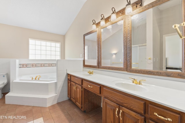 bathroom featuring tile patterned floors, vanity, tiled tub, toilet, and lofted ceiling