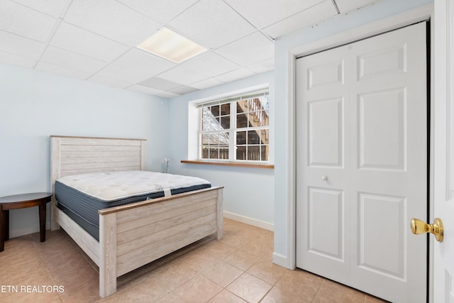 tiled bedroom featuring a drop ceiling and a closet