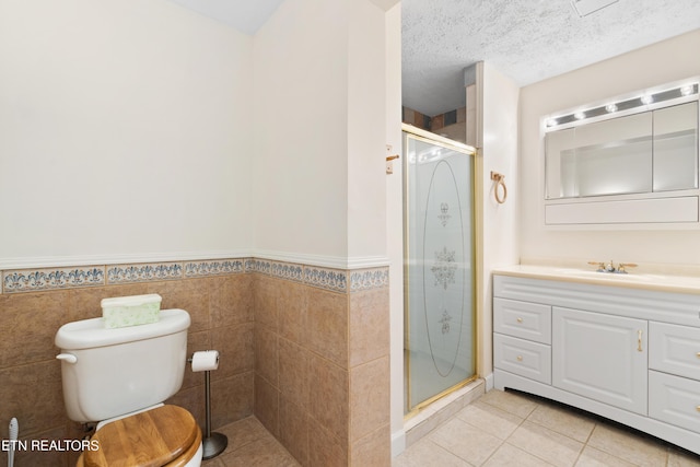 bathroom with vanity, tile patterned flooring, toilet, a textured ceiling, and walk in shower