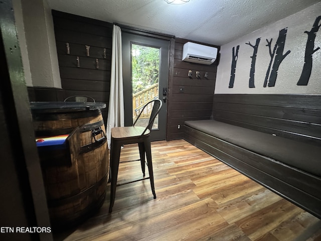 interior space featuring wood-type flooring, a textured ceiling, a wall mounted AC, and wood walls