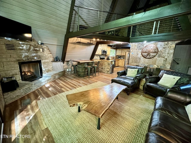 living room featuring a fireplace, wood-type flooring, and high vaulted ceiling